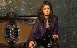 woman wearing purple zip-up leather jacket sitting on couch in room